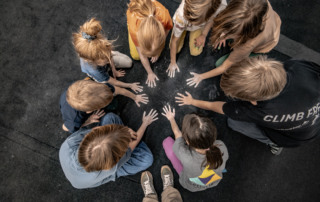 Mehrere Kinder sitzen im Kreis und machenmit Chalk an den Händen Abdrücke